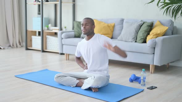 Young African Man Meditating on Yoga Mat at Home alt