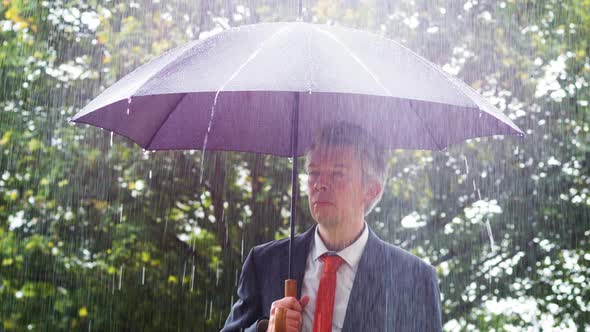 Businessman Sheltering Underneath an Umbrella in the Rain