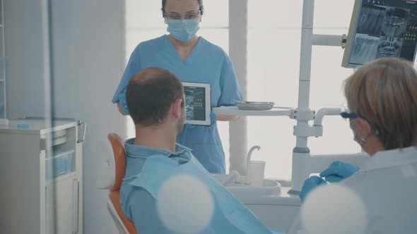 Dentistry Assistant Holding Digital Tablet with Teeth x Ray Scan alt