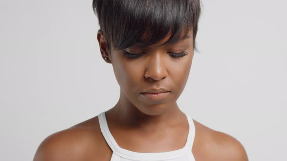 Mixed Race Black Woman Watching Down and Then To the Camera and Touches Her Hair alt
