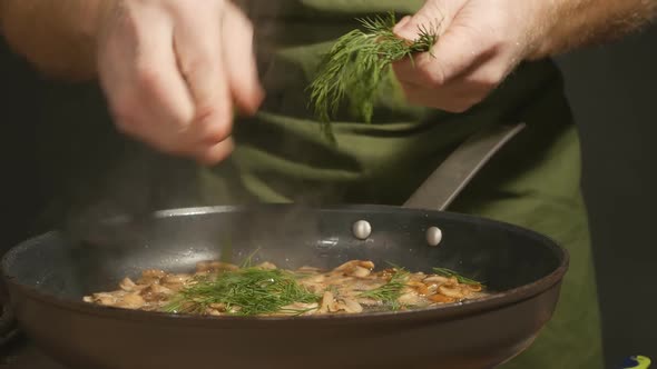 Male Chef Adds Green Dill to Fried Mushrooms in a Hot Frying Pan