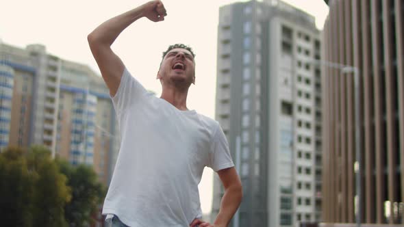 Young Handsome Man Winner Celebrating in the City Center at Sunset alt