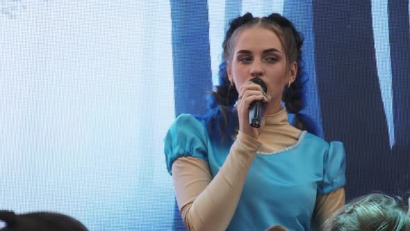 Young Woman with Microphone Leads a Children's Party in an Entertainment Center alt