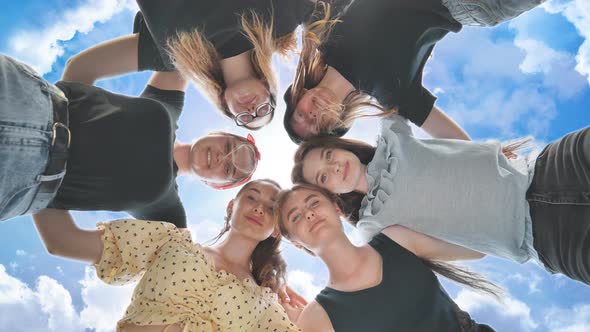 Happy Girls Friends Hugging in a Circle on the Background of the Fairy Sky alt