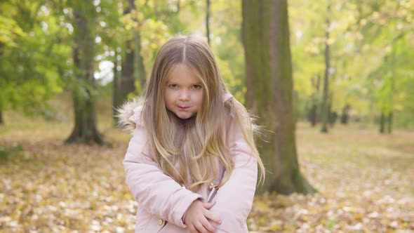 Cute Little Caucasian Girl Eats a Snack and Smiles at the Camera in a Park alt