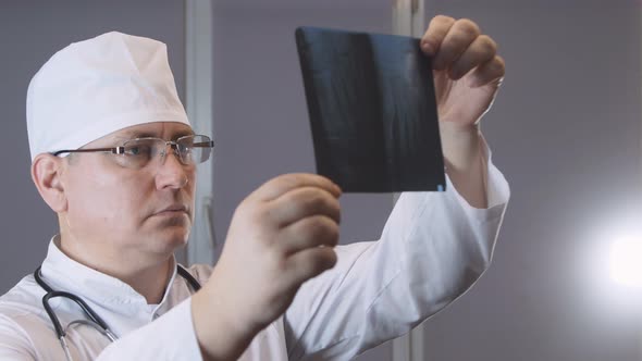 Caucasian female doctor surgeon in a medical mask examines a computed tomography of the spine before alt