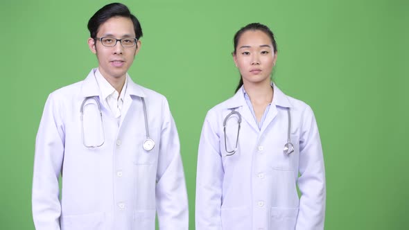Young Happy Asian Couple Doctors with Arms Crossed Together
