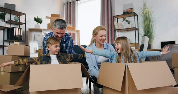 Parents Playing with their Son and Daughter which Sitting in Carton Boxes while Mom and Dad alt