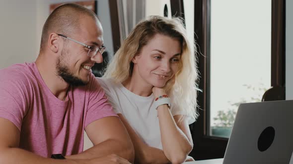 Blonde woman and man sitting in cafe with laptop making video calling by webcam alt