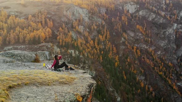 Woman Enjoy the Sunset Sitting on Top of a High Mountain alt