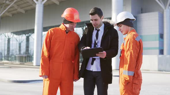 Investor of the Project in a Black Suit Examining the Building Object with Construction Workers in alt