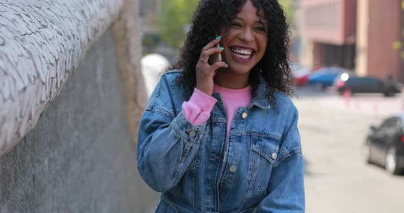 Happy woman talking by phone with laugh in city