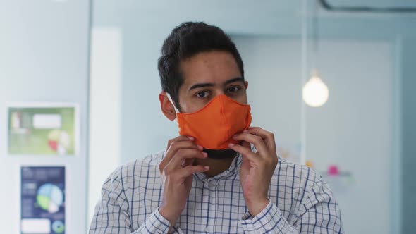 Portrait of middle eastern man adjusting his face mask at modern office alt