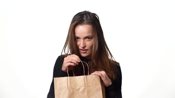 beautiful woman in a black sweater looks mysteriously in a paper packbag alt