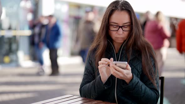 A Closeup Portrait of an Adult Woman with Glasses Sitting at a Table in an Outdoor Cafe Writing a alt