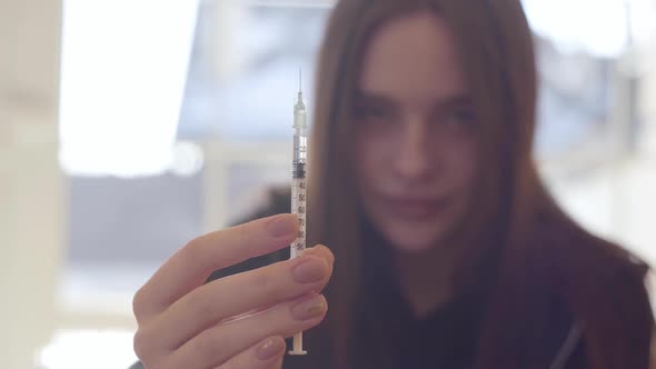 Young Woman Holding the Syringe with the Drug alt