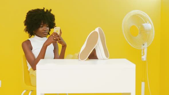 Black Woman Is Relaxing On Chair Using Mobile Phone alt