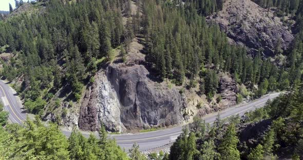 Aerial view of vehicles driving along a winding mountain highway in Washington State. alt