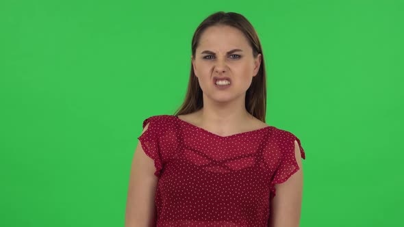 Portrait of Tender Girl in Red Dress Is Showing Disgust for Bad Smell or Taste. Green Screen alt