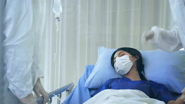 Covid19 Doctors in Ppe Suit with Face Mask Treating Young Woman Patient on Bed From Coronavirus alt