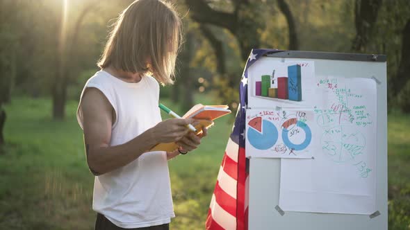 Focused Young Man Standing at Whiteboard with American Flag Writing Ideas with Pen alt