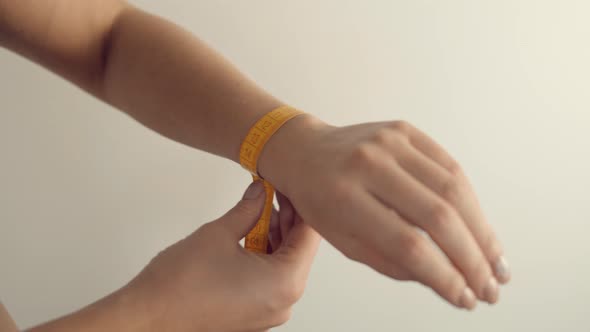 Girl Measuring Wrist With Measure Tape. Woman Measuring Wrist Progress Weight Loss. Measuring Tape. alt