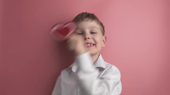 Caucasian Boy Holds Heart Shaped Valentine and Dancing on Pink Background