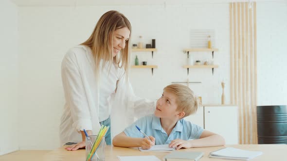 Schoolboy Preparing His Homework for School Classes His Mother Stands Beside