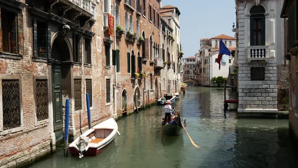 Gondola in a canal and Venetian flag in Venice alt