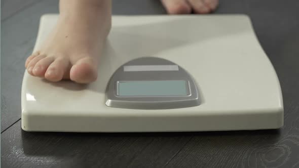 Normal Healthy Body Weight, Woman Stepping on Scales to Measure Dieting Results alt