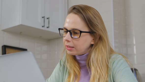 Freelancer woman in glasses talking on laptop computer webcam at home in 4k video alt