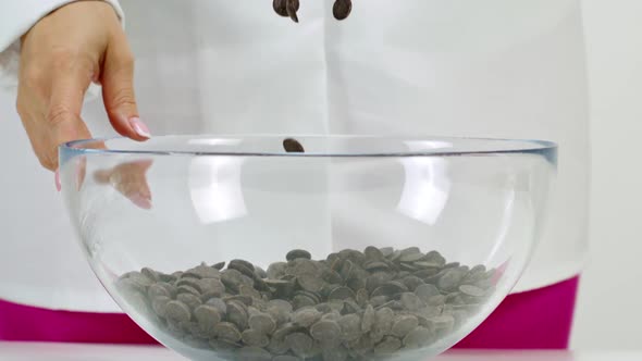 Closeup Chocolatier Pours Dark Chocolate Chips on White Background, Slow Motion