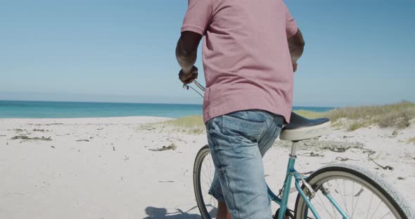 Senior man with a bike at the beach alt