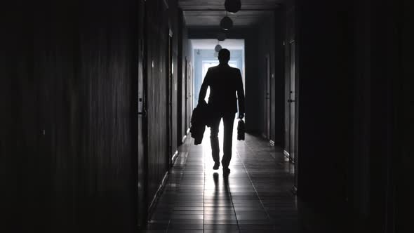 Rear View of Businessman Walking along Dark Hallway