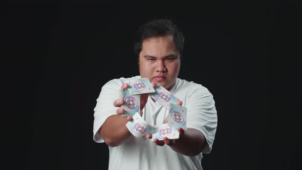 Asian Man Shows Trick With Playing Cards, Cardistry On Black Background alt
