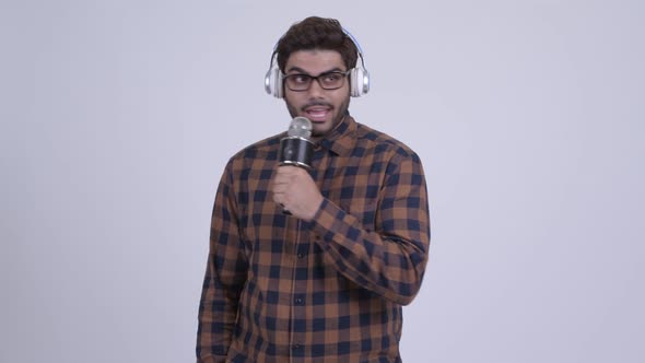 Happy Young Bearded Indian Hipster Man Listening To Music and Singing alt