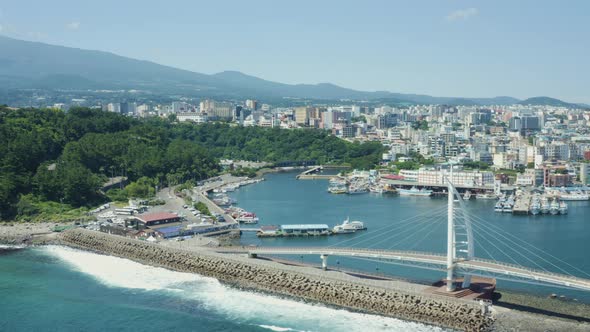A drone shot showing the port town of Jeju Island and Halla Mountain.