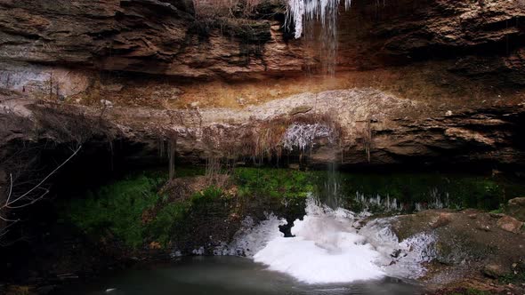 Small Waterfall with Portions of Ice on Wet Rocks and Greenery alt
