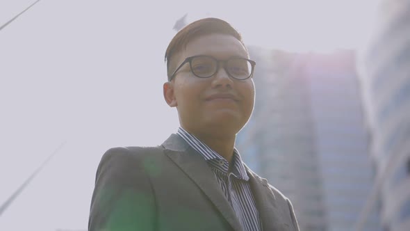 Portrait handsome Asian businessman smiling and looking at camera standing on the urban city.