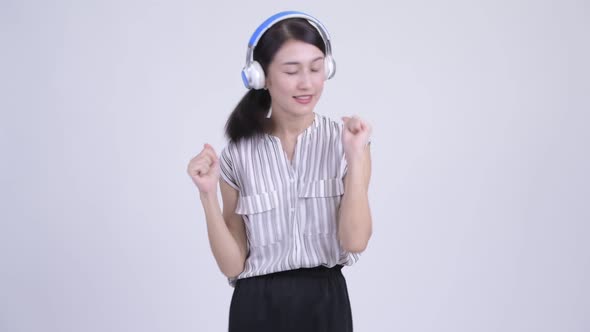 Beautiful Asian Businesswoman Listening To Music and Looking Guilty alt