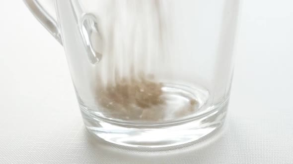 Close-up of glass filling with instant tea granules slow-mo video alt