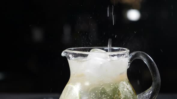 Sparkling Soda Water Being Poured Into Glass Jar Filled with Sliced Lime Mint Leaves and Ice alt