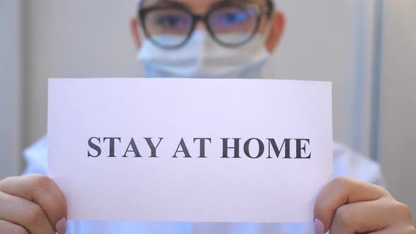 Female Doctor Is Holding a Picture with the Inscription Stay at Home During Coronavirus Epidemic alt