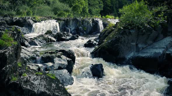 Wild River Going Around Rock Formation On Sunny Day alt