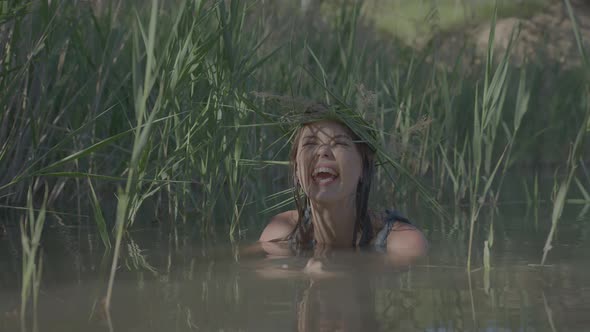 Beautiful Water Maiden with a Wreath on Her Head Smiling Comes Out of the Water alt