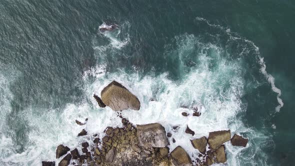 Top down aerial view of giant ocean waves crashing and foaming in coral beach alt