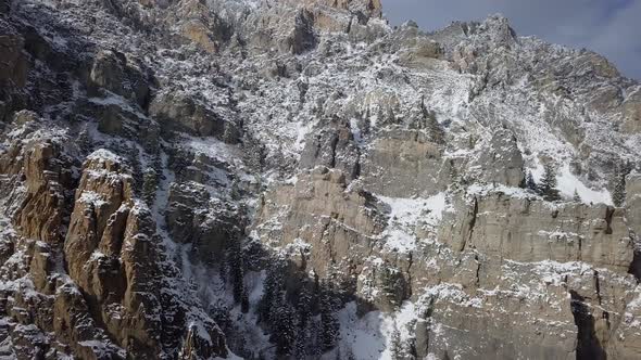 Snow covered rocky cliffs lit up by the sun alt