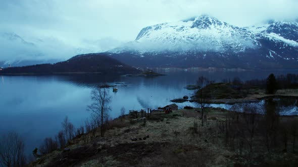 Low Aerial View of a fishing boat inside a Norwegian Fjord during late evening in Winter alt