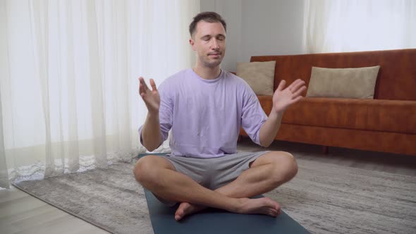 A Man Meditates at Home in the Lotus Position Does Namaste
