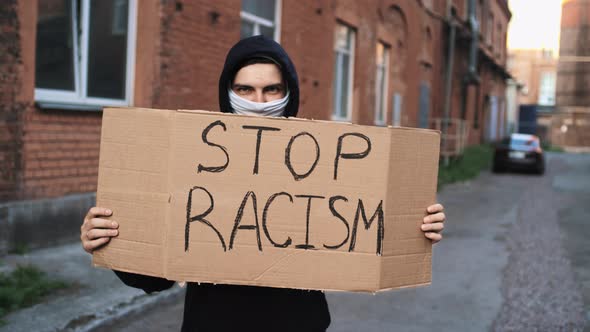 Man in Mask Stands with Cardboard Poster in Hands  AM I NEXT AND STOP RACISM